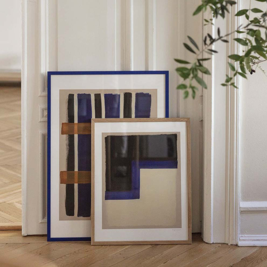 Two framed posters leaning behind a white, wooden door.