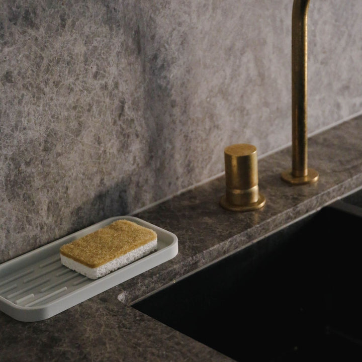 Natural lighting, perspective view of a sponge placed on a kitchen sink.