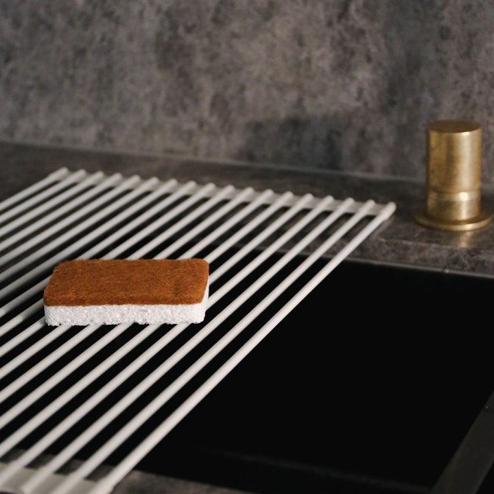 Natural lighting, perspective view of a sponge placed on a kitchen sink.