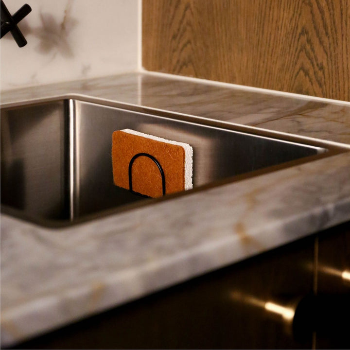 Natural lighting, perspective view of a sponge placed on a sponge holder inside the sink area.