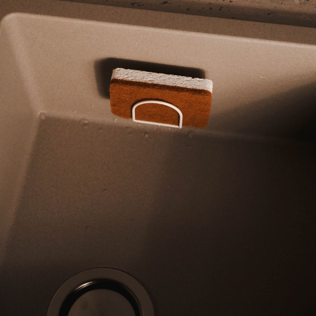 Natural lighting, top view of a sponge placed on a sponge holder inside the sink area.