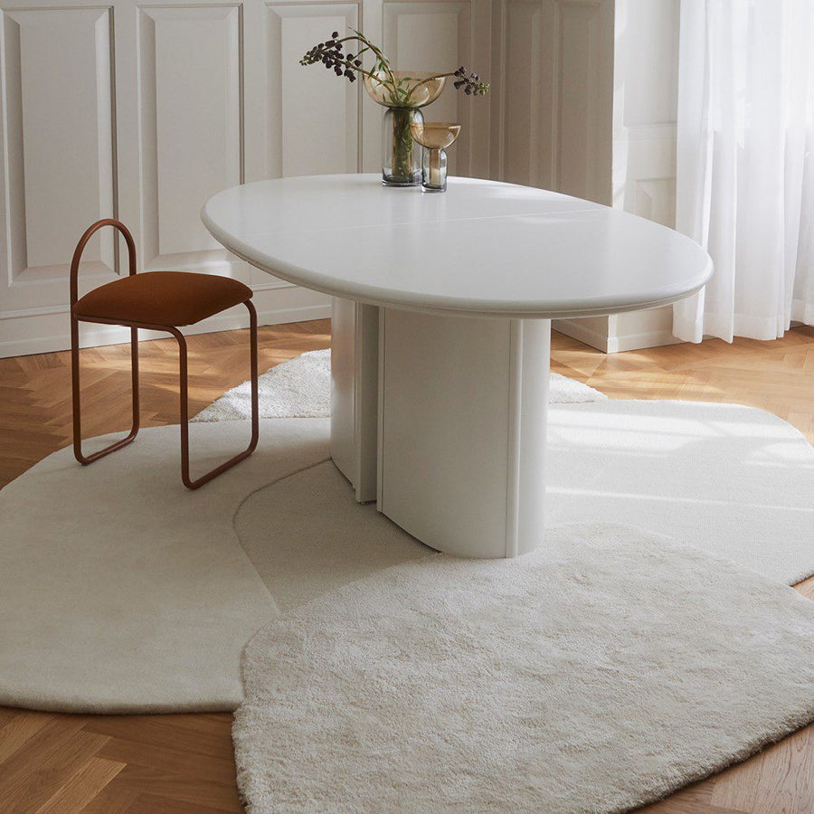 Natural lighting, perspective view of a rug topped with a chair and table