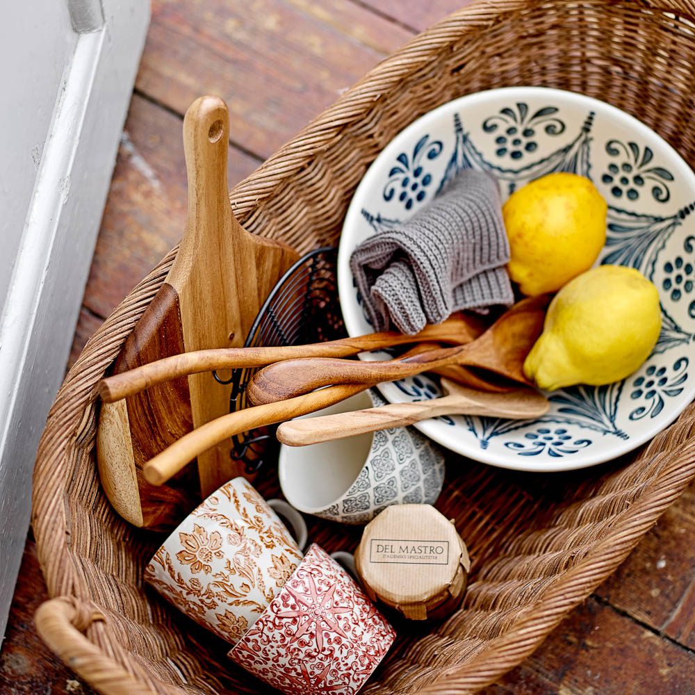 The large serving spoon made from acacia wood in a rattan picnic basket.