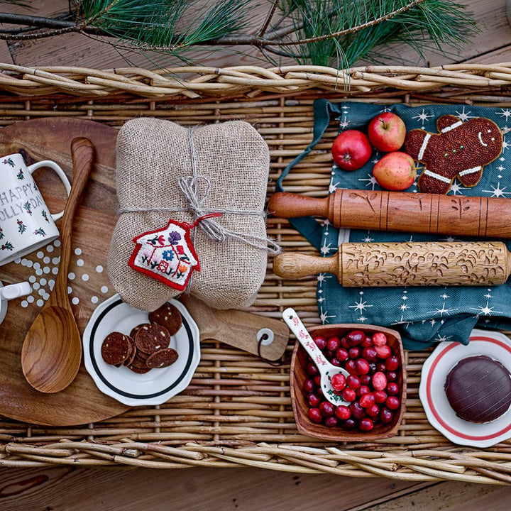 The large serving spoon made from acacia wood with rolling pins and snacks on a rattan basket.