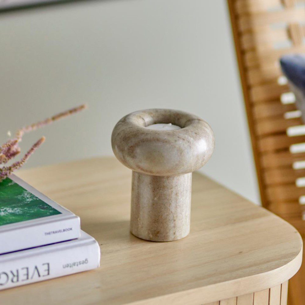 Natural lighting, perspective view of a decorative candle holder next to books on top of a table.