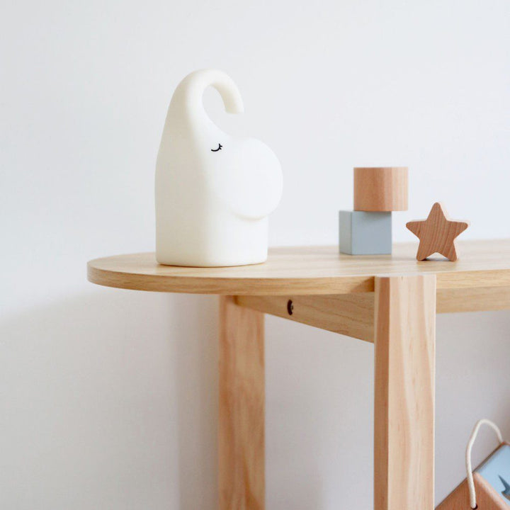 Natural light, perspective view of an animal-shaped lamp placed next to décor on a table.