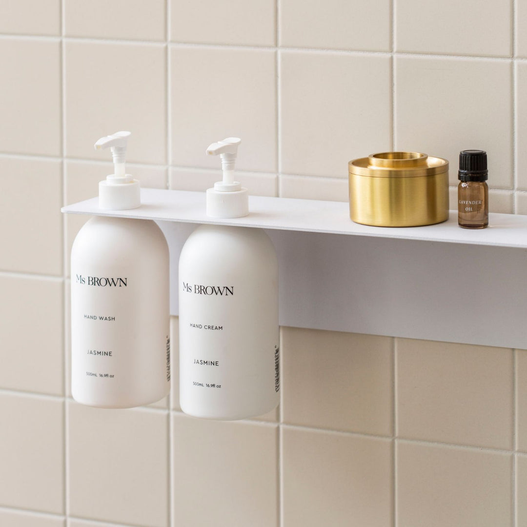 Perspective view of the White DESIGNSTUFF Shelf w/ Dual Soap Dispenser Holder 40cm in a bathroom with white tiles