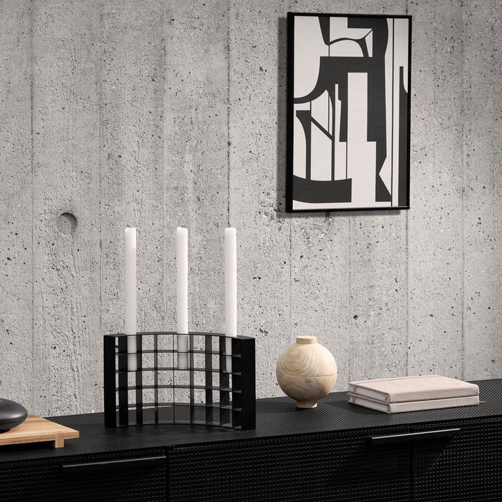 Mesh candle holder on a table with a monochrome wall art on concrete wall.