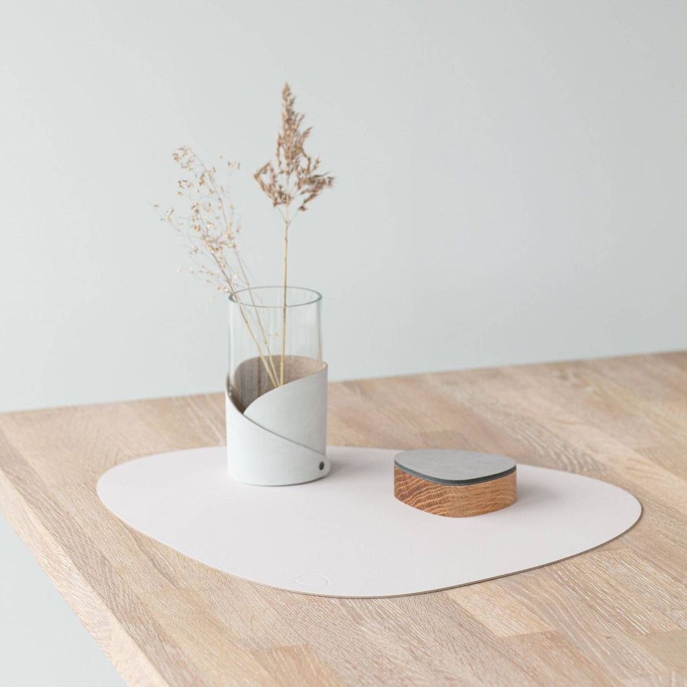 Nupo curve table mat on a dining table, made from reused leather and natural rubber.