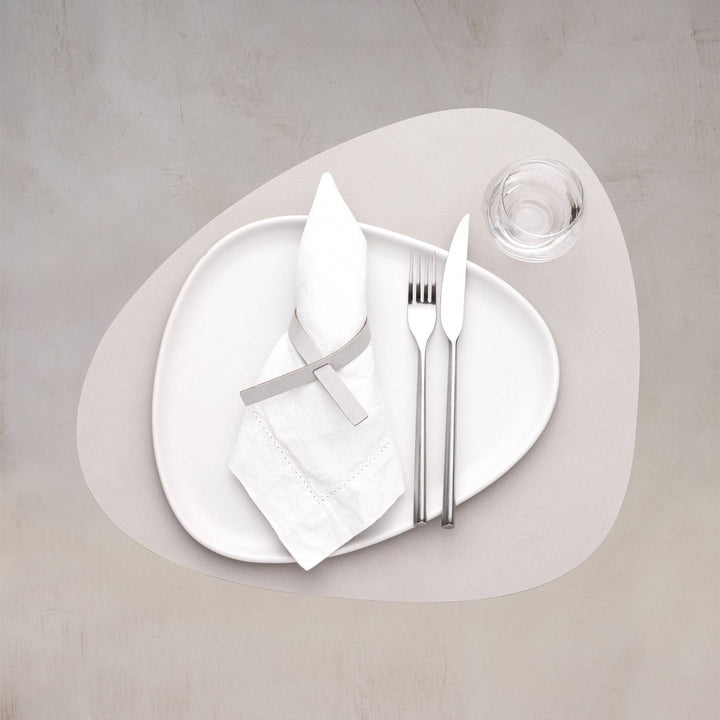 A tableware set with Nupo curve table mat on a dining table. It is made from reused leather and natural rubber.