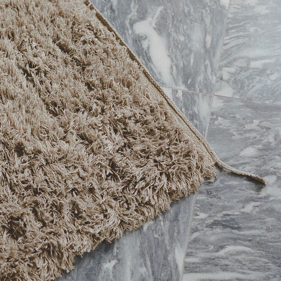 A detailed packshot of hand-woven Luminary Sun wool rug by Linie Design.