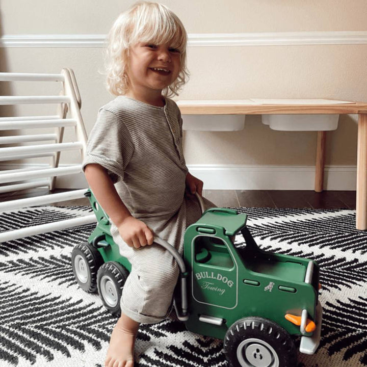 A boys is sitting on the sturdy ride-on Mack truck from Moover.