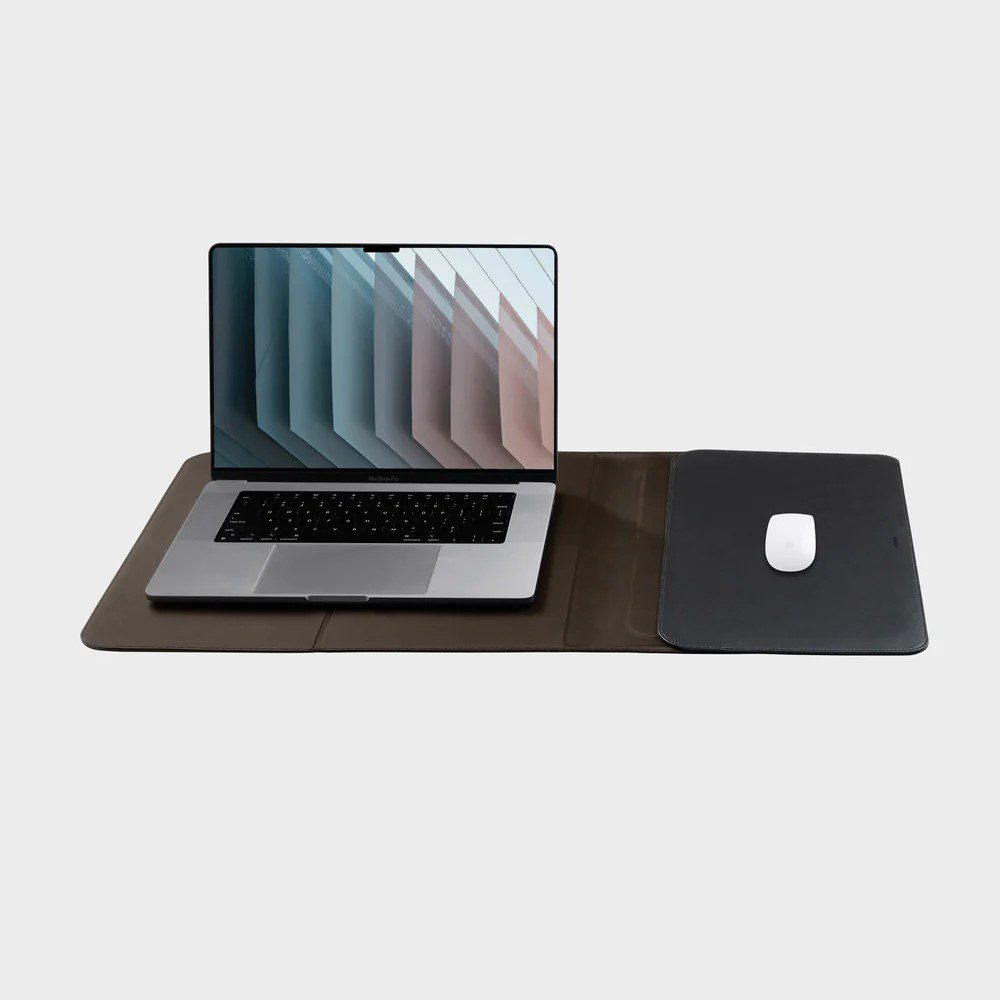 Studio lighting, perspective view of a laptop computer and mouse placed on top of a spread out hybrid laptop sleeve and deskmat