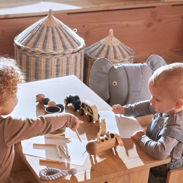 Two kids are playing with stacking toys on the table with Circus basket set of 2 in the background.