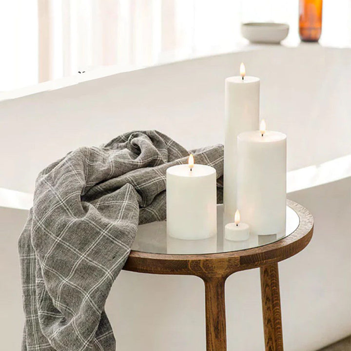 Three flameless pillar candles next to a blanket.