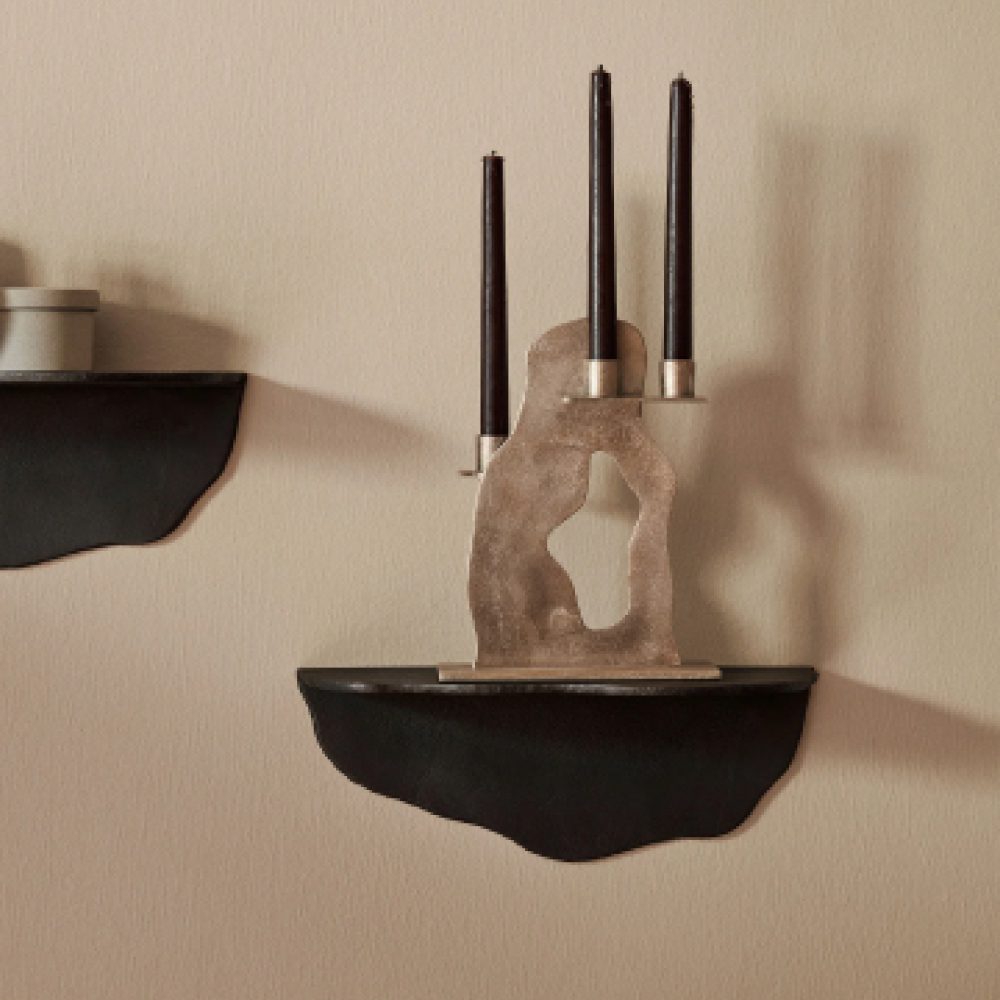 Natural lighting, perspective view of a black, irregular shaped aluminum rack with candle holders placed on top.